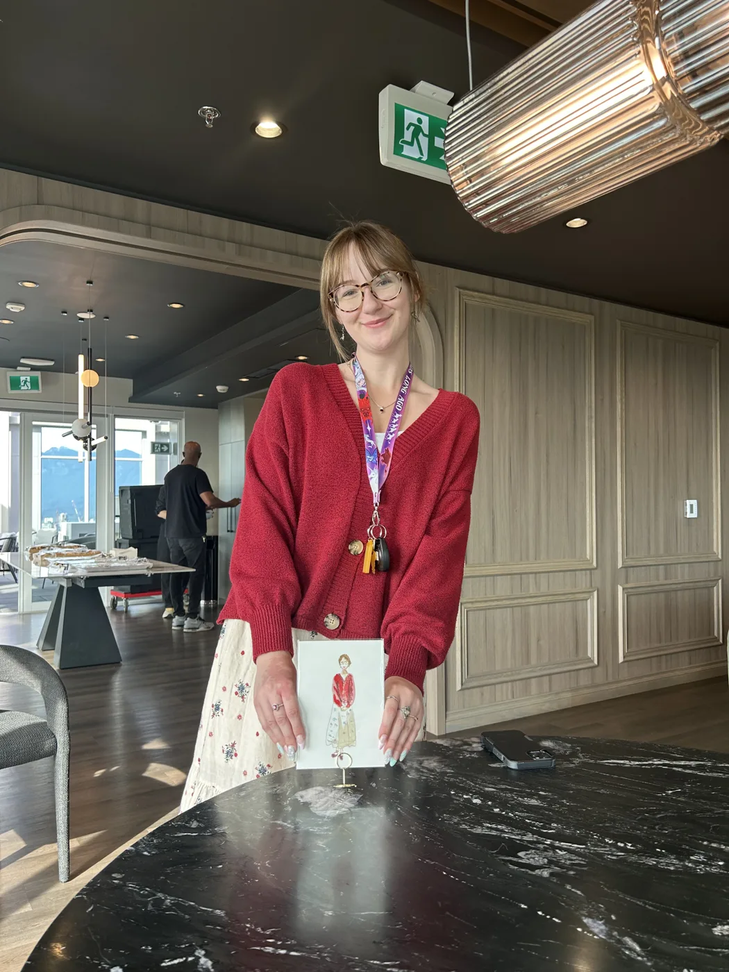 Guest in a red sweater holding her finished watercolour illustration