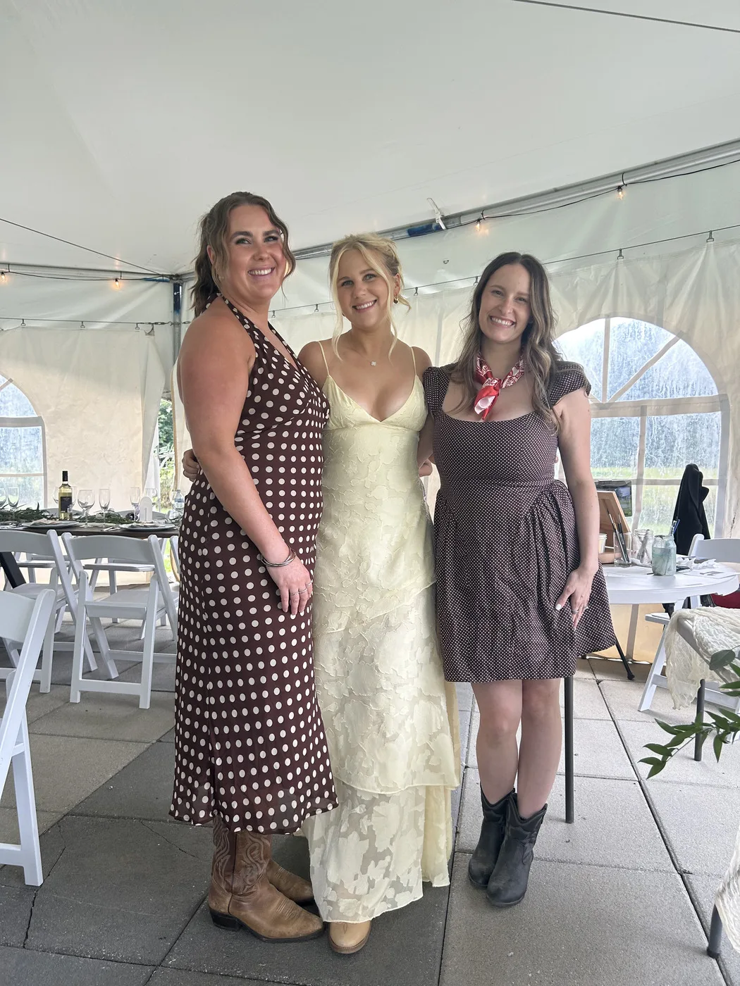 Guest photo of three women standing arm-in-arm in patterned dresses and cowboy boots at a wedding reception