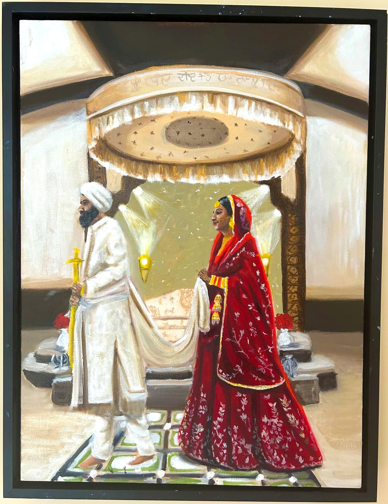 Original wedding oil painting of a Sikh groom in white holding a ceremonial sword beside the bride in her red lehenga beneath the palki canopy, photographed in its black frame