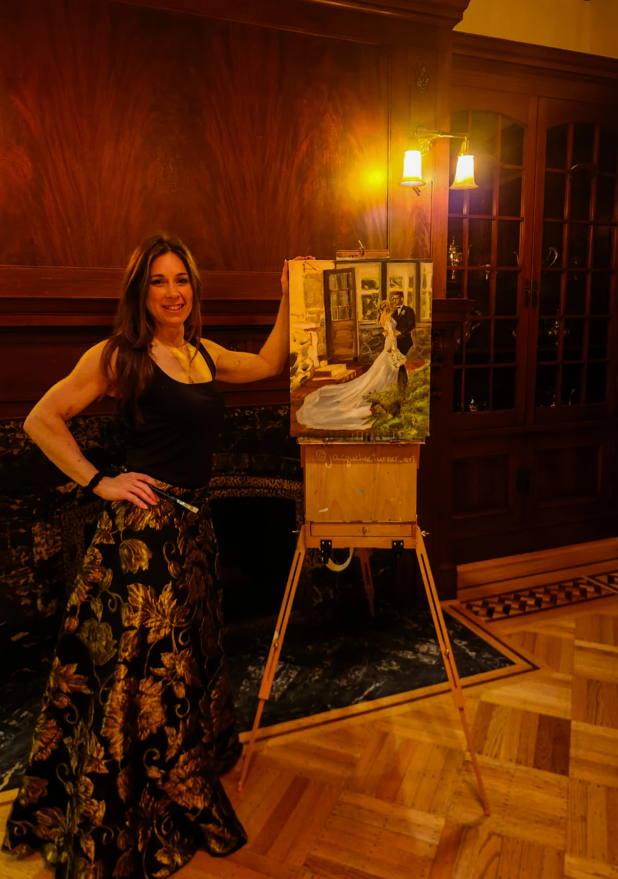 Jacqueline Turner beside the wedding painting on her easel during the reception