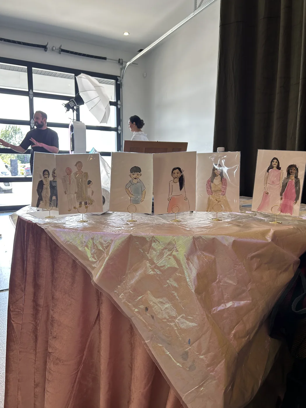 Six guest illustrations in protective sleeves on gold stands at a birthday party